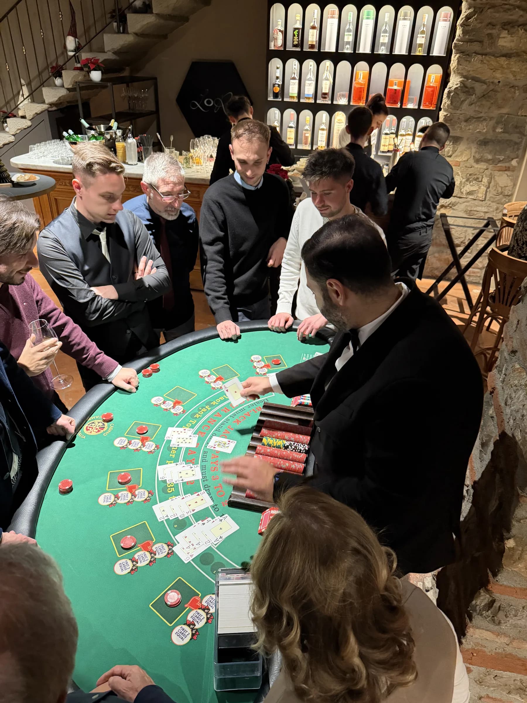 Croupier che distribuisce le carte al tavolo da blackjack mentre gli ospiti seguono la mano