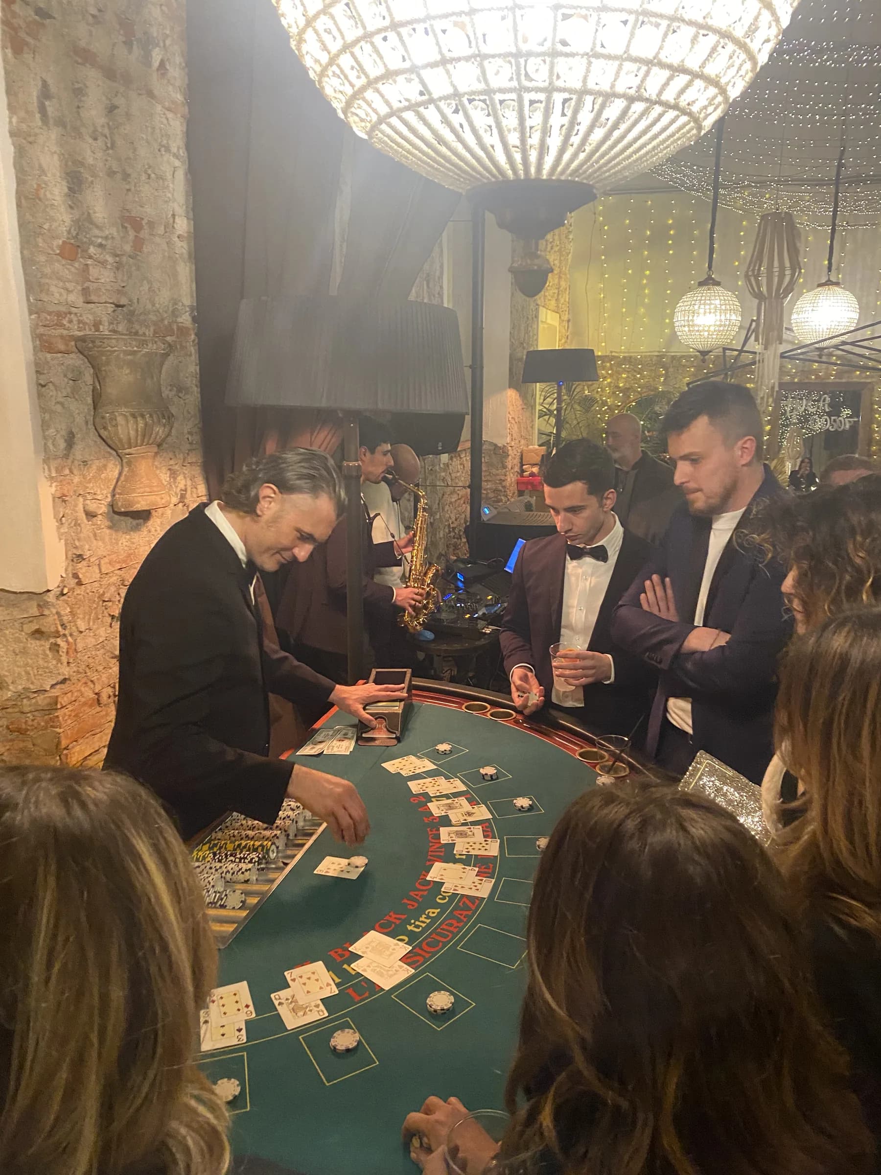 Ospiti raccolti intorno a un tavolo da blackjack sotto un lampadario