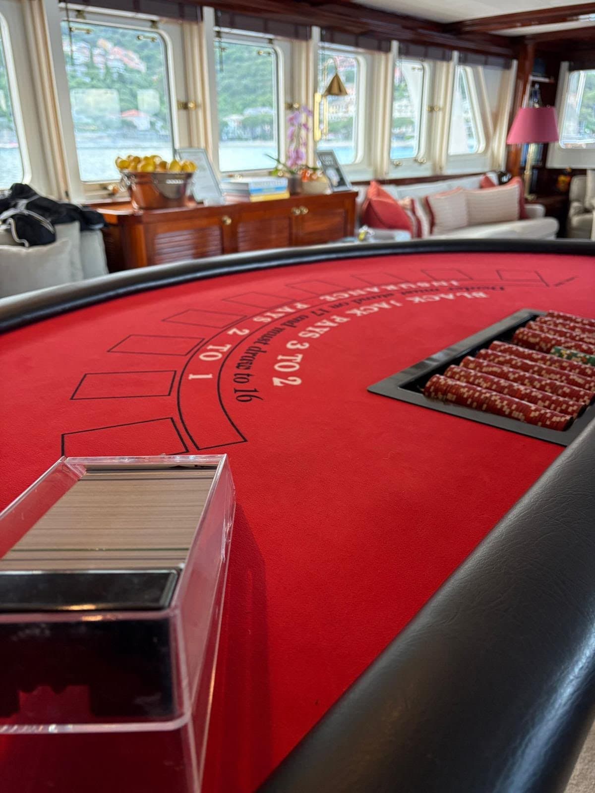 Tavolo blackjack nel salone di uno yacht, con mare e costa oltre gli oblò