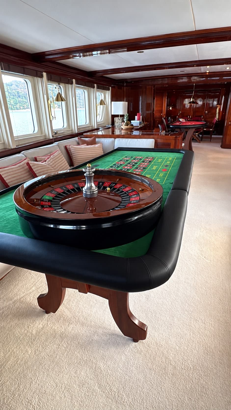 Tavolo roulette nel salone di uno yacht, con il mare visibile dagli oblò