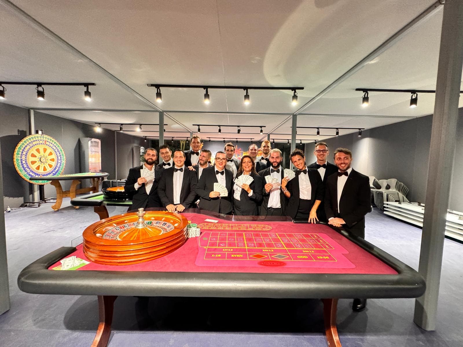 Squadra Fun Casinò in smoking intorno a un tavolo da roulette, in una location indoor