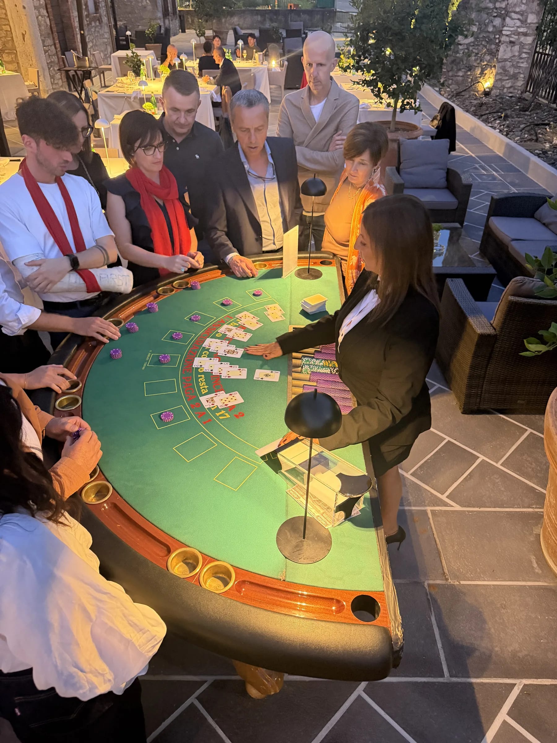 Blackjack all’aperto di sera, con croupier e ospiti al tavolo